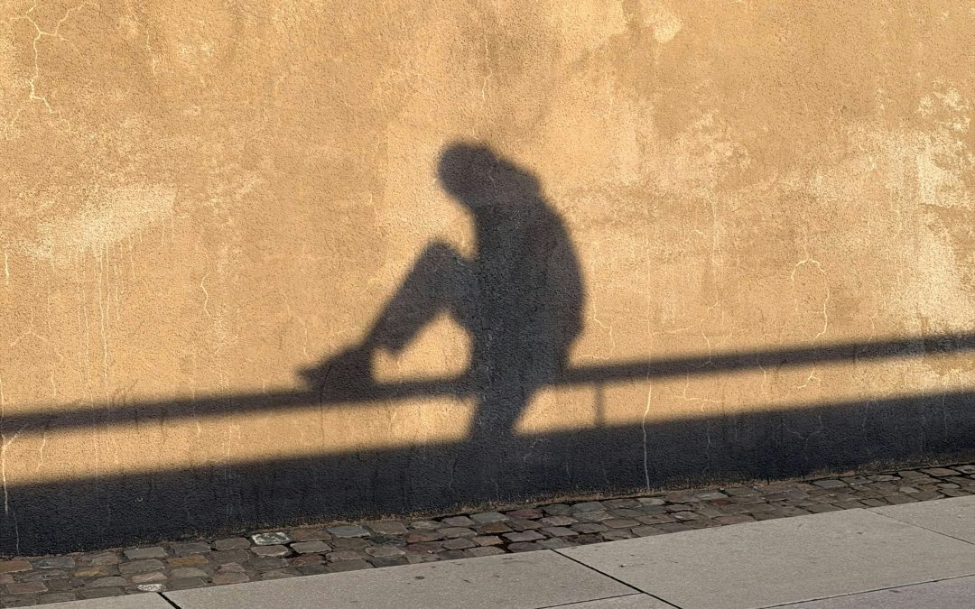 shadow of a person sitting against a sunlit wall