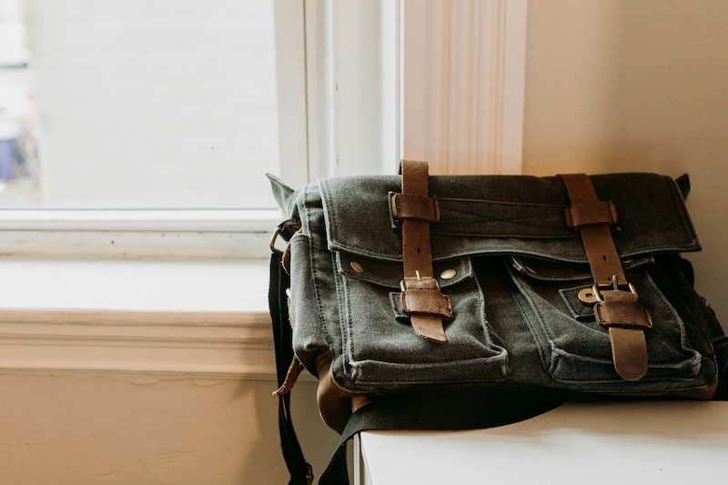 A worn canvas school satchel resting on a sunlit windowsill